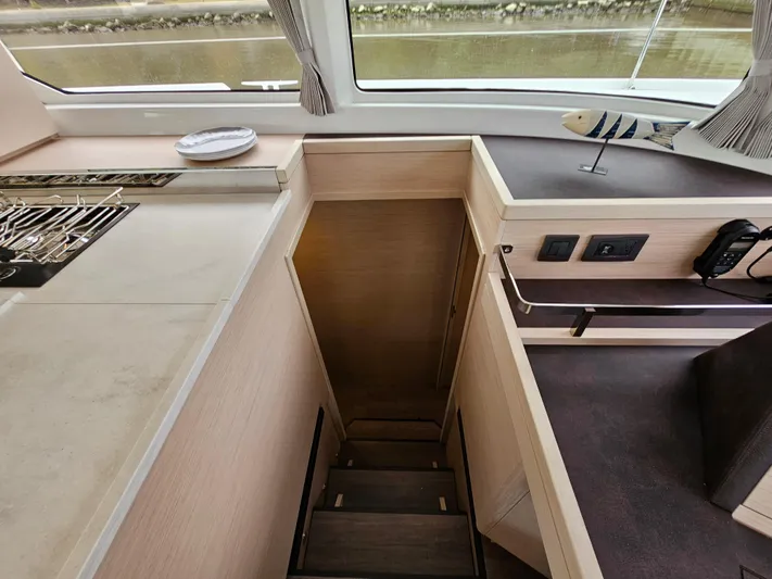 Yacht Photos Pics Interior of 2024 Lagoon 46 yacht showing stairs, kitchen counter, and window view.