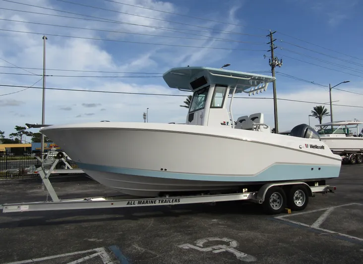  Yacht Photos Pics 2025 Wellcraft 243 Fisherman boat on trailer, parked outdoors under a cloudy sky.