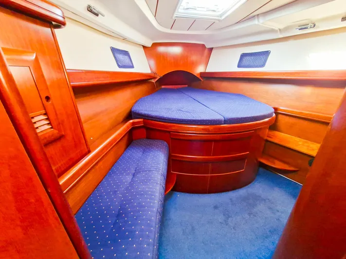  Yacht Photos Pics Interior cabin of 2004 Beneteau Oceanis 423 with blue upholstery and wooden finish.