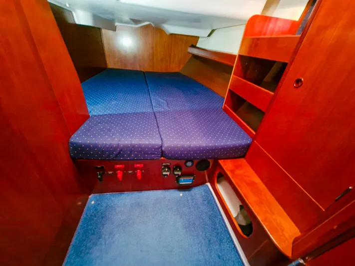  Yacht Photos Pics Interior cabin of 2004 Beneteau Oceanis 423 with blue polka dot bedding and wooden shelves.