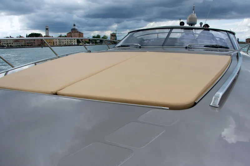  Yacht Photos Pics 2006 Riva Rivale 52 yacht with beige sunpad, under cloudy sky, near historic buildings.