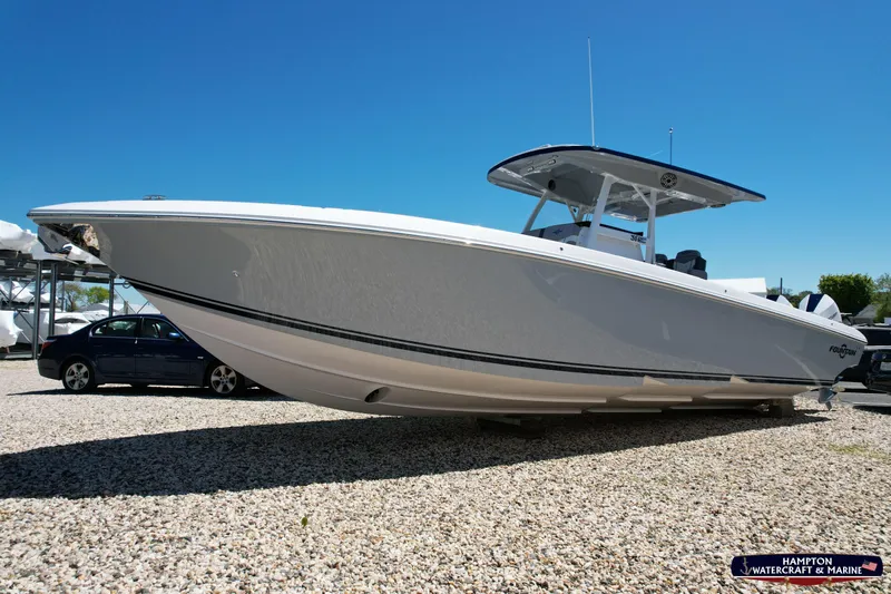 Mundinger Brokerage Yacht Photos Pics 2023 Fountain 34 SC boat displayed outdoors on gravel, under clear blue sky.