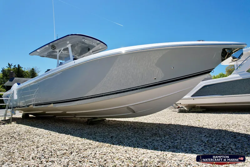 Mundinger Brokerage Yacht Photos Pics 2023 Fountain 34 SC boat displayed outdoors on gravel under clear blue sky.