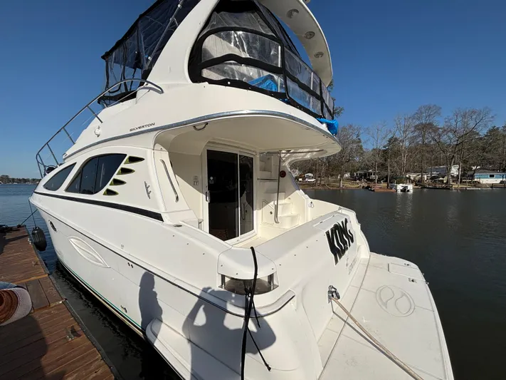 Kong Yacht Photos Pics 2005 Silverton 38 Sport Bridge yacht docked by a serene lake.