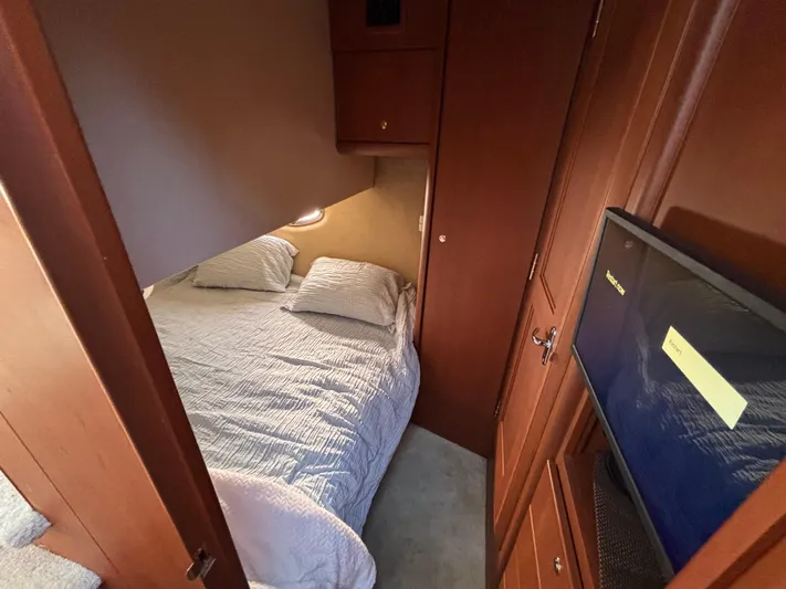 Kong Yacht Photos Pics 2005 Silverton 38 Sport Bridge cabin with bed, wooden cabinetry, and mounted TV.
