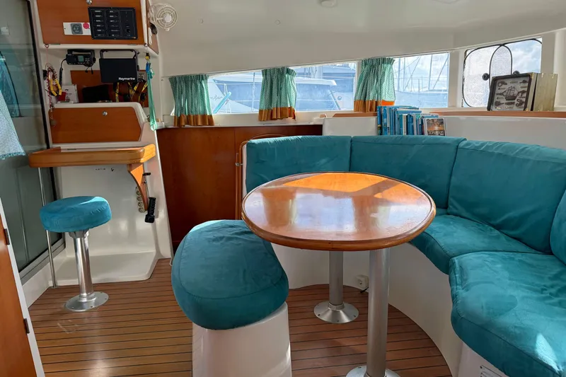  Yacht Photos Pics Interior of 2003 Lagoon 380 catamaran with teal seating and wooden table.