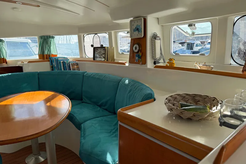  Yacht Photos Pics Interior of 2003 Lagoon 380 catamaran with teal seating and wooden table.