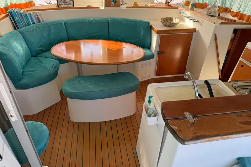  Yacht Photos Pics Cozy interior of 2003 Lagoon 380 catamaran with teal seating and wooden table.