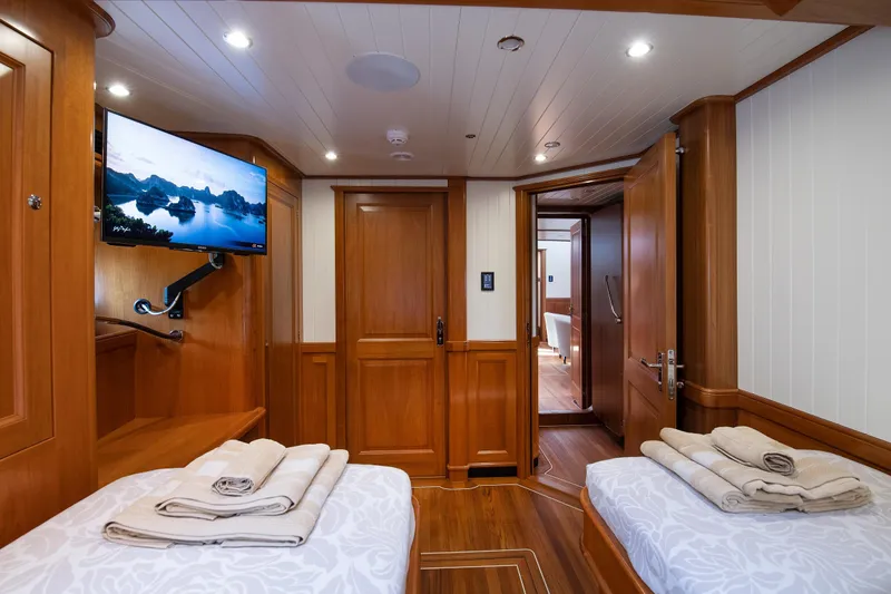 Melody Yacht Photos Pics Luxurious 2022 Ridas Custom Yacht cabin with twin beds, wooden interior, and mounted TV.