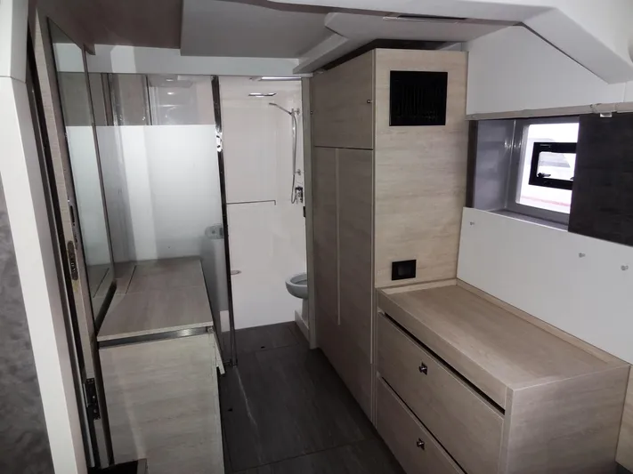 Aquaholic Yacht Photos Pics Modern interior of 2019 Leopard 50 yacht with wooden cabinetry and compact bathroom.