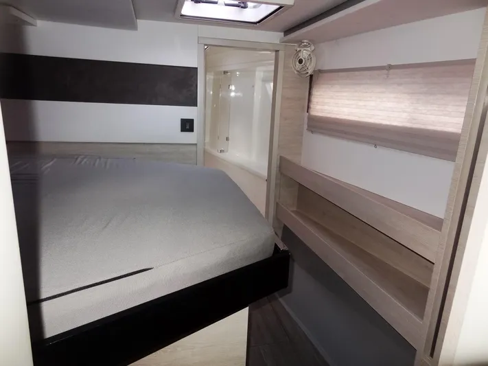 Aquaholic Yacht Photos Pics 2019 Leopard 50 yacht interior bedroom with bed, shelves, and window.