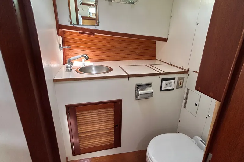 Bugle Boy Yacht Photos Pics Compact boat bathroom with sink, toilet, and wood accents in a 1994 John Williams Stanley 36.