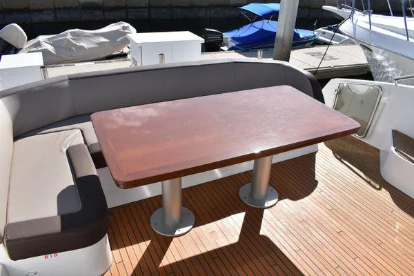 Be Water My Friend Yacht Photos Pics Outdoor seating area on 2016 Beneteau GT49 yacht with wooden table and cushioned benches.