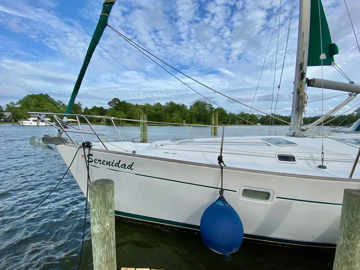 Serenidad Yacht Photos Pics Sailboat "Serenidad," a 1999 Beneteau 411, docked on a calm, scenic waterway.