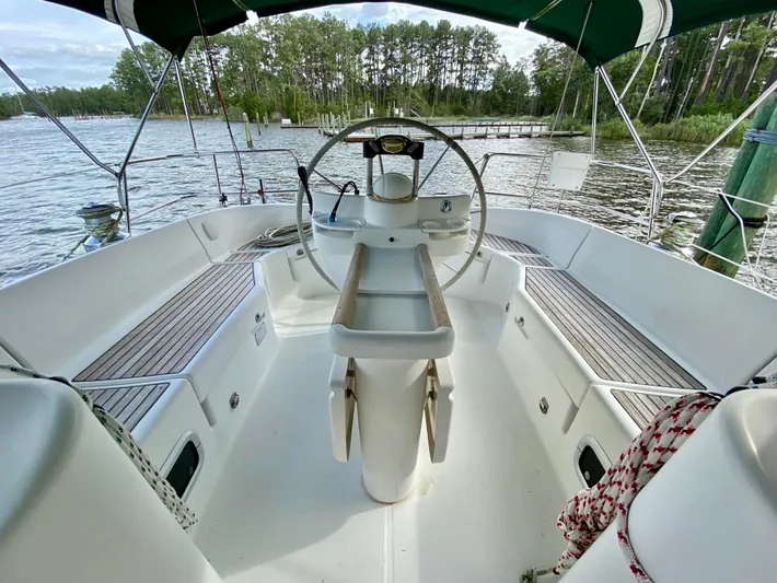 Serenidad Yacht Photos Pics Cockpit of 1999 Beneteau 411 sailboat with steering wheel, docked by a scenic lake.