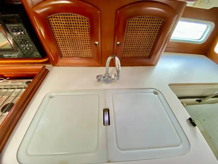 Serenidad Yacht Photos Pics Interior of 1999 Beneteau 411 yacht kitchen with sink and wooden cabinets.