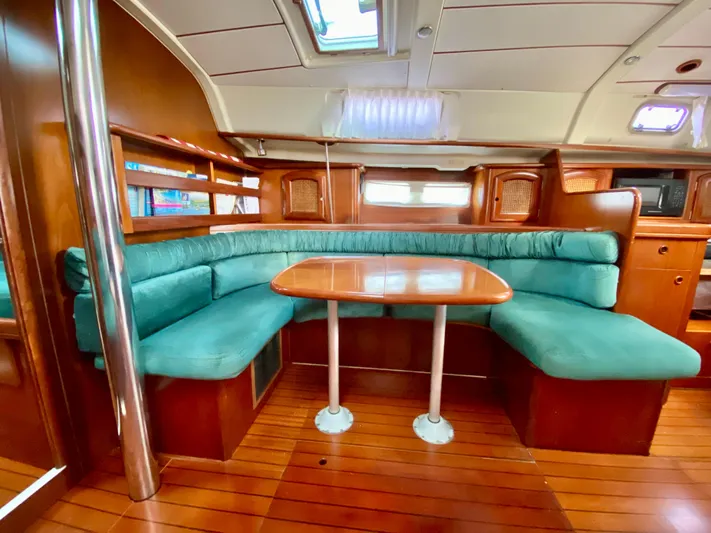 Serenidad Yacht Photos Pics Luxurious interior of 1999 Beneteau 411 yacht with teal seating and wooden table.