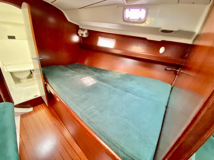 Serenidad Yacht Photos Pics Cozy cabin interior of 1999 Beneteau 411 sailboat with wooden finish and green bedding.