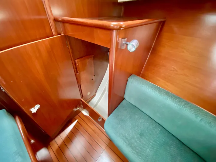 Serenidad Yacht Photos Pics Interior of 1999 Beneteau 411 sailboat with wooden cabinetry and green seating.