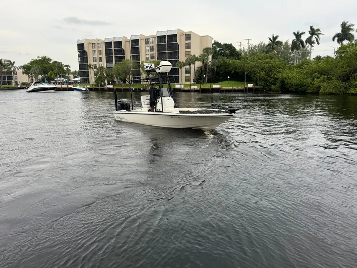  Yacht Photos Pics 2024 Pathfinder 2500 Hybrid boat cruising on a river near residential buildings.