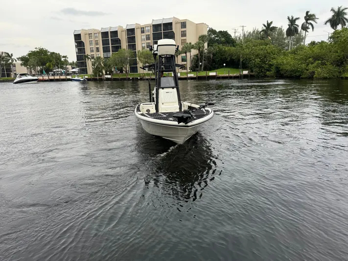  Yacht Photos Pics 2024 Pathfinder 2500 Hybrid boat cruising on a calm river near waterfront buildings.