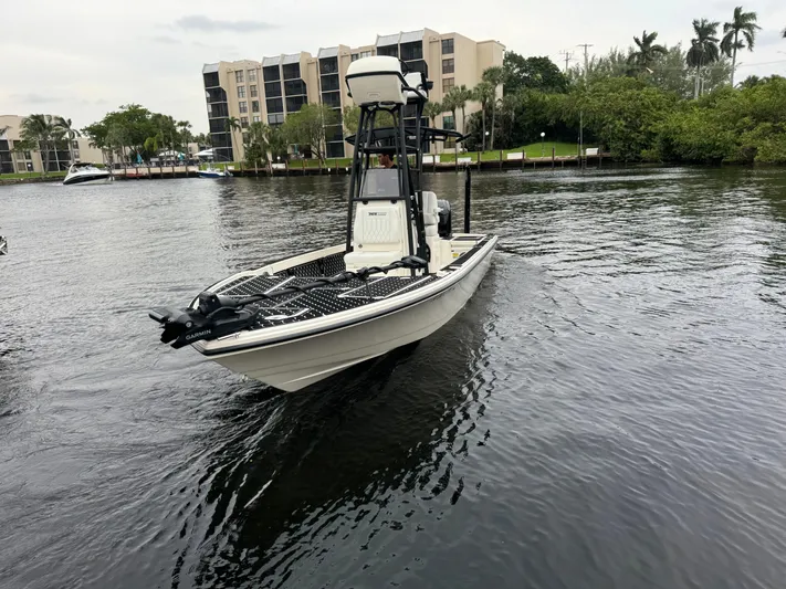  Yacht Photos Pics 2024 Pathfinder 2500 Hybrid boat on a calm river near modern buildings.