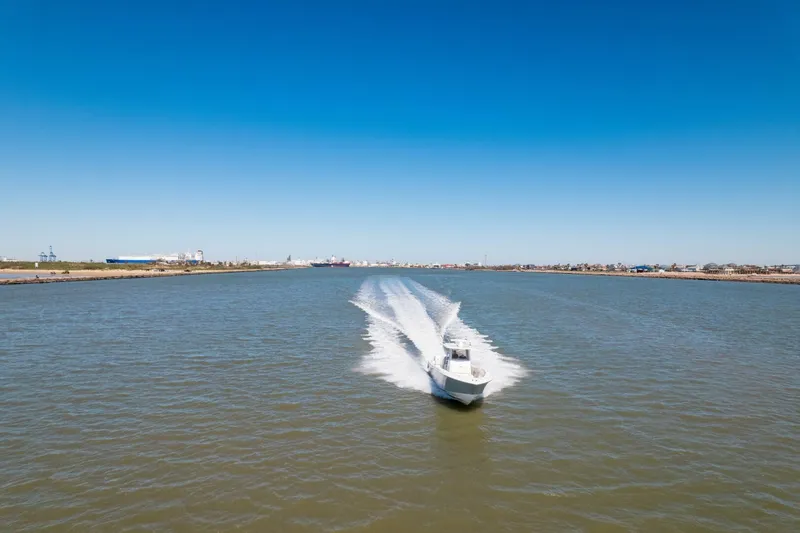  Yacht Photos Pics 2019 Invincible 39 Open Fisherman boat cruising on a wide river under clear blue skies.