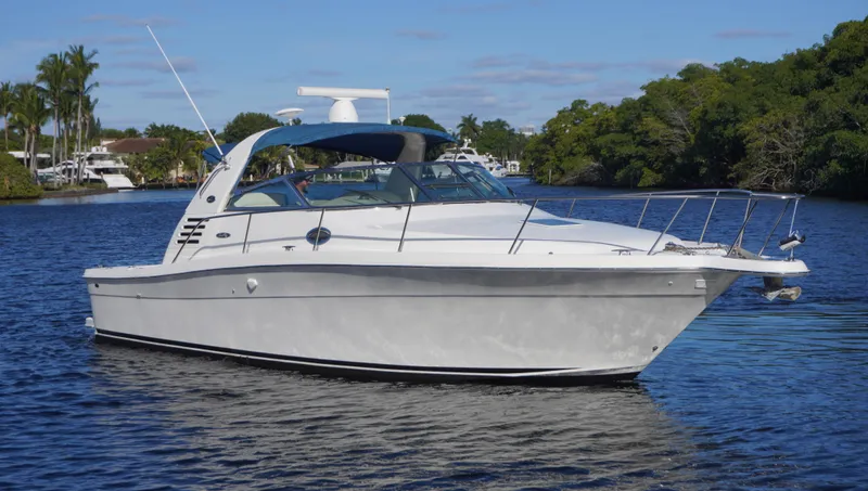 In Deep Ship II Yacht Photos Pics 2002 Sea Ray 340 Amberjack boat on calm water with lush greenery in the background.