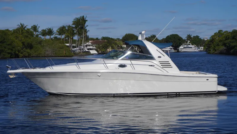 In Deep Ship II Yacht Photos Pics 2002 Sea Ray 340 Amberjack boat on calm water, surrounded by trees and clear sky.