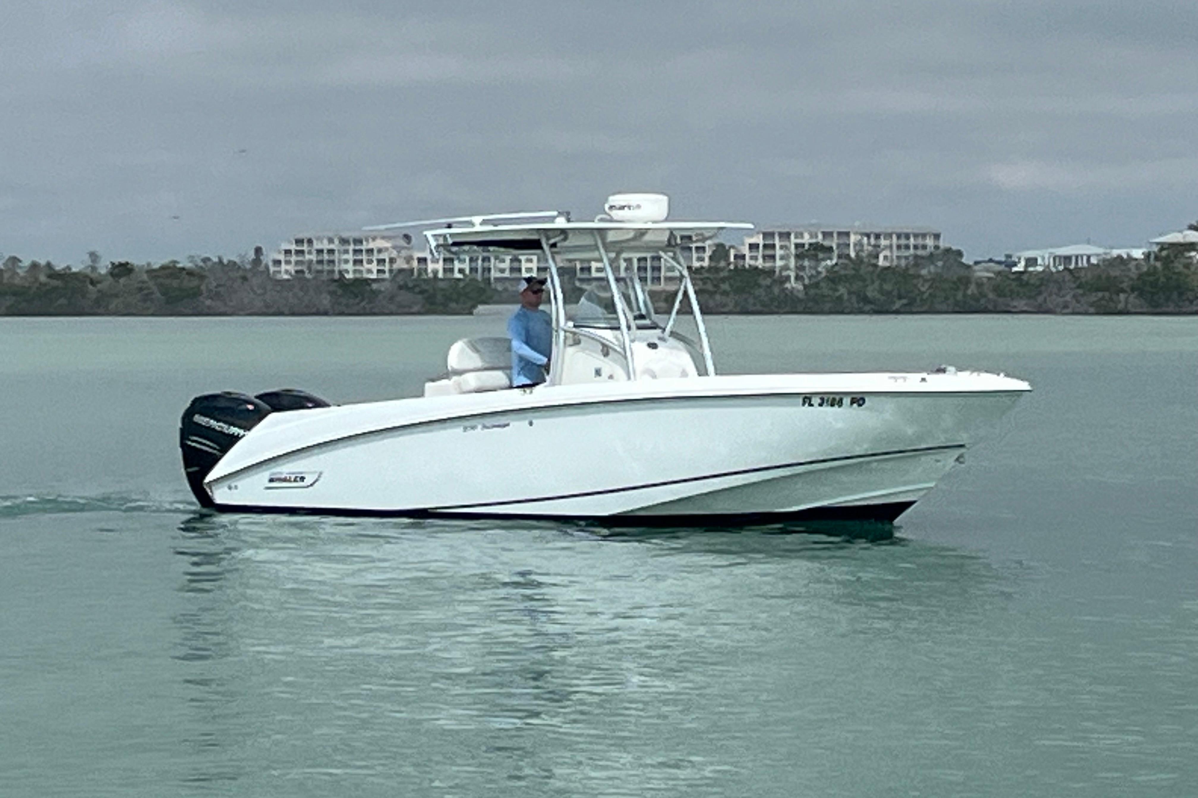 2007 Boston Whaler 270 Outrage boat cruising on calm waters near shoreline.