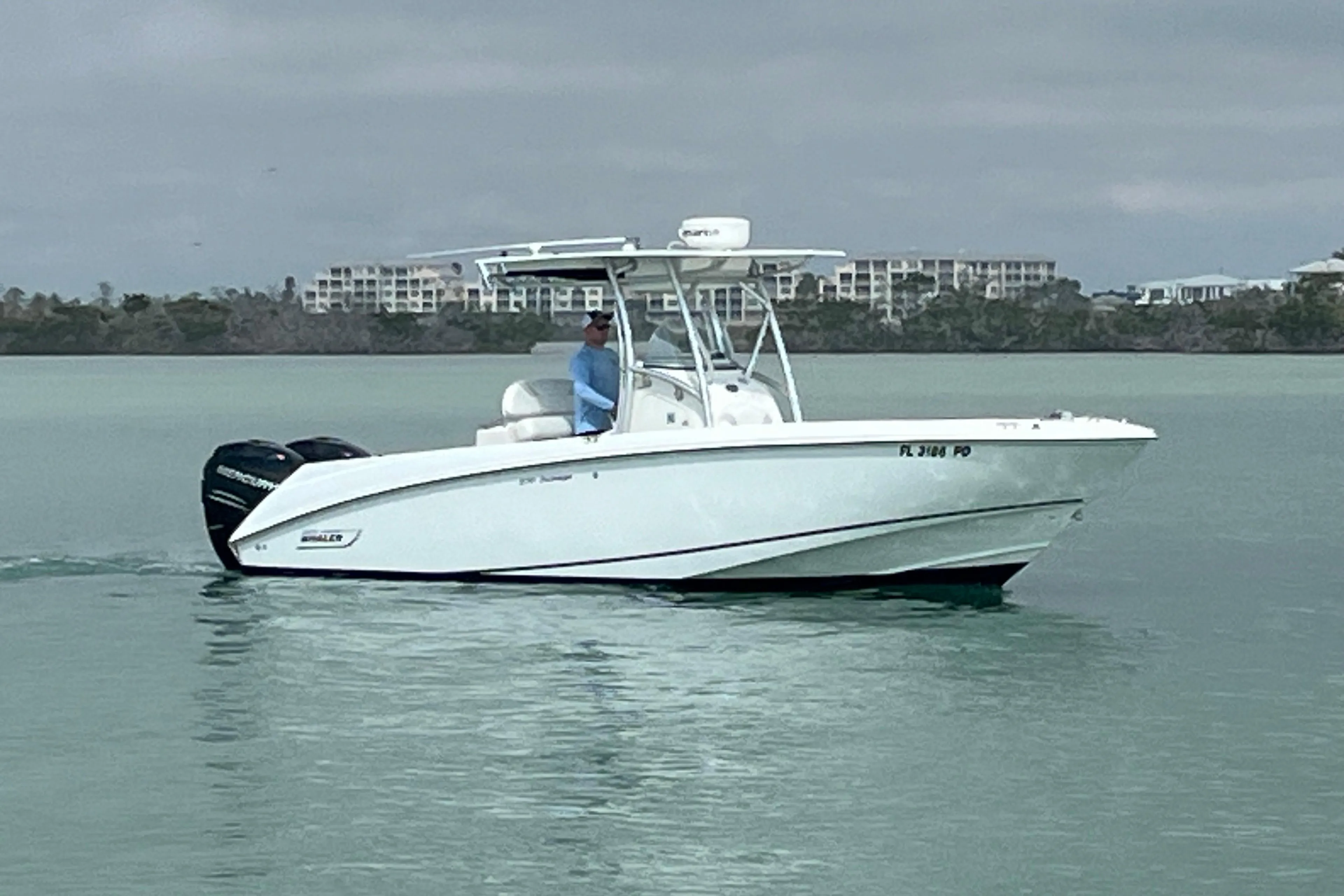 2007 Boston Whaler 270 Outrage boat cruising on calm waters near shoreline.
