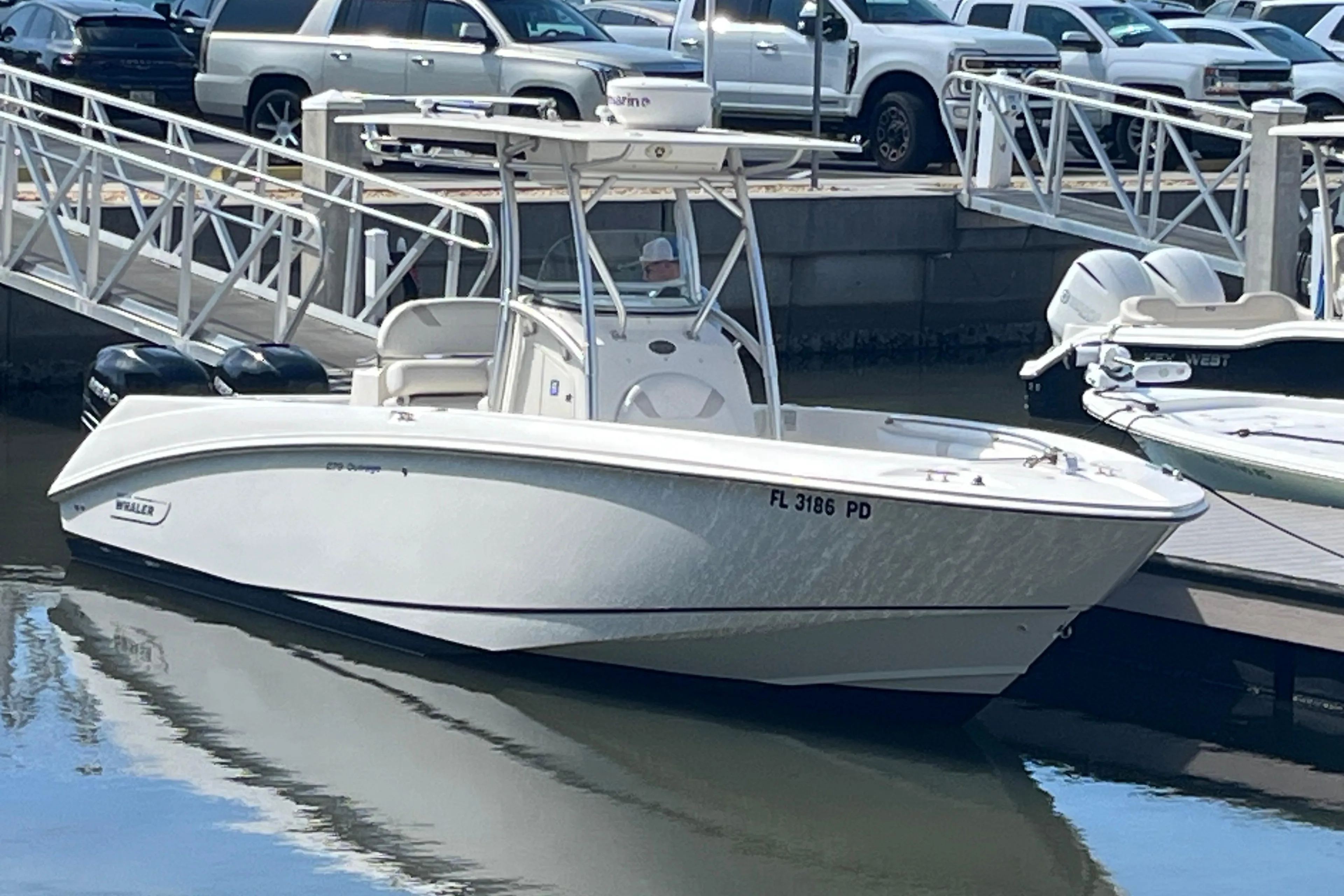 2007 Boston Whaler 270 Outrage boat docked at marina with vehicles in background.