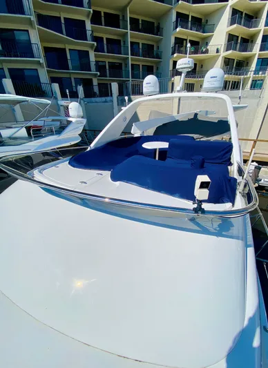 Last Minute Yacht Photos Pics 2002 Azimut 55 yacht with blue sunbathing area, docked near modern apartments.