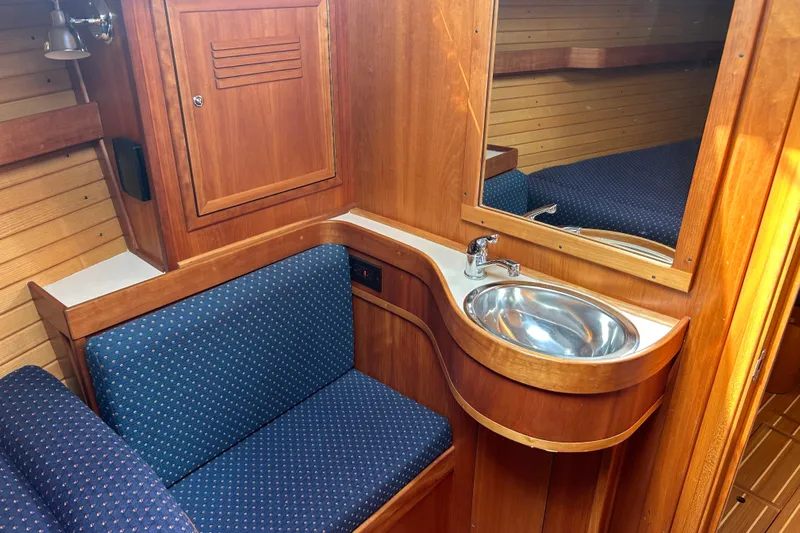 Indigo Yacht Photos Pics 2002 Sabre 362 yacht interior with wooden cabinetry, blue seating, and stainless steel sink.