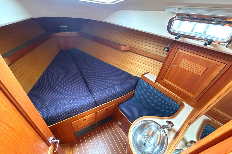Indigo Yacht Photos Pics Cozy cabin interior of 2002 Sabre 362 sailboat with wood paneling and blue upholstery.
