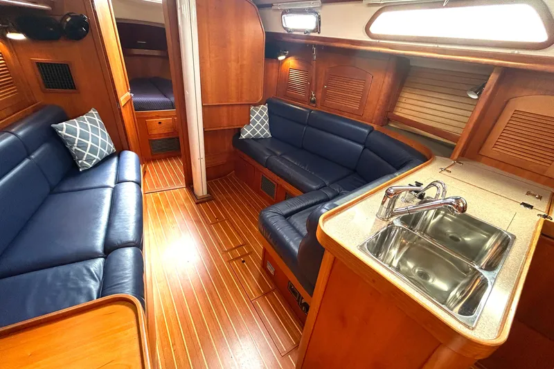 Indigo Yacht Photos Pics Interior of 2002 Sabre 362 yacht with blue seating, wooden flooring, and kitchenette.