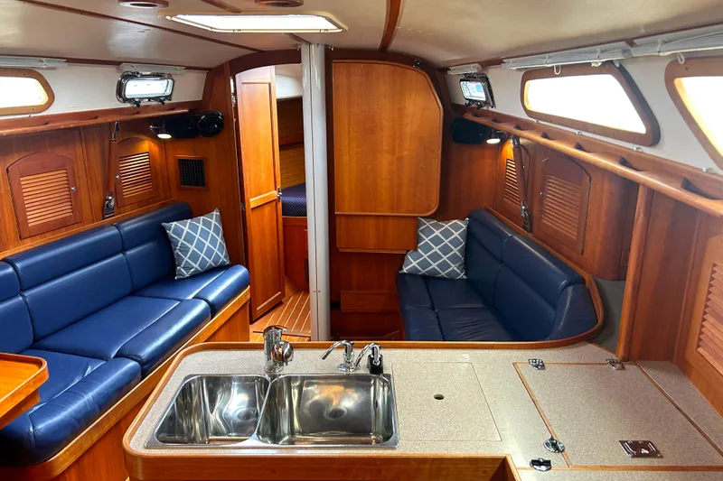 Indigo Yacht Photos Pics Interior of 2002 Sabre 362 sailboat with blue seating and wooden cabinetry.