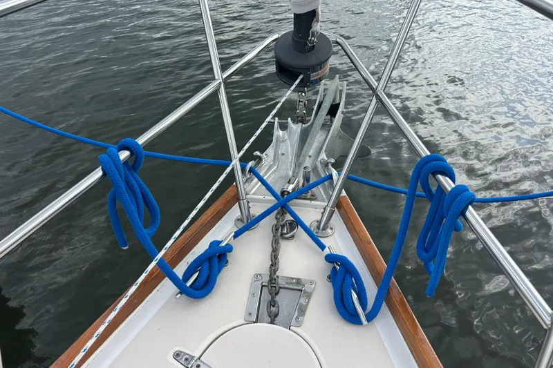 Indigo Yacht Photos Pics Bow of 2002 Sabre 362 sailboat with blue ropes and anchor over water.