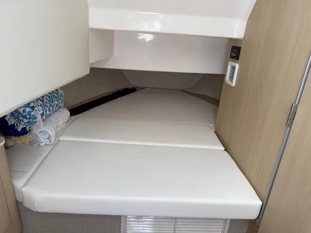  Yacht Photos Pics 2023 Regal 33 SAV cabin interior with white cushioned bed and wooden accents.