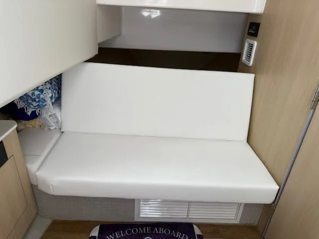  Yacht Photos Pics 2023 Regal 33 SAV interior with white cushioned seating and "Welcome Aboard" mat.