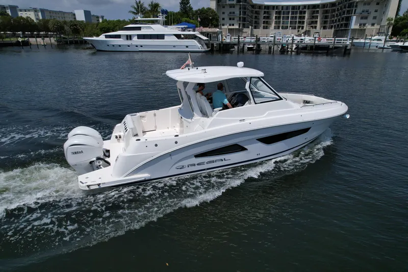  Yacht Photos Pics 2023 Regal 33 SAV boat cruising on a calm waterway near a marina.