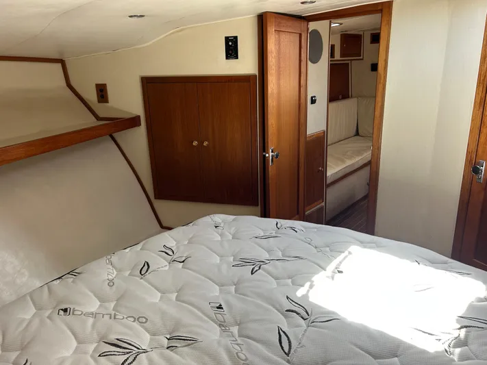 No Slack Yacht Photos Pics 2002 Albemarle 410 Express Fisherman cabin with bed, wooden cabinets, and doorway to seating area.