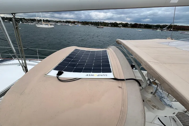 A Domani Yacht Photos Pics Beneteau Oceanis 411 sailboat with solar panel on deck, anchored in a scenic harbor.