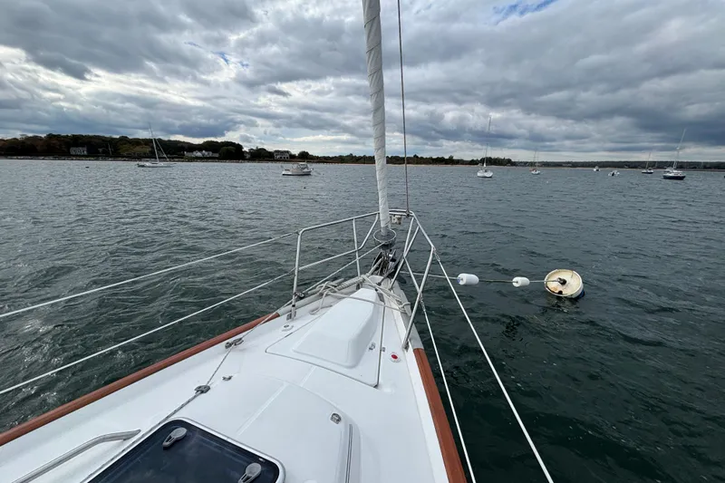 A Domani Yacht Photos Pics Bow view of 2002 Beneteau Oceanis 411 sailboat on calm waters under cloudy sky.