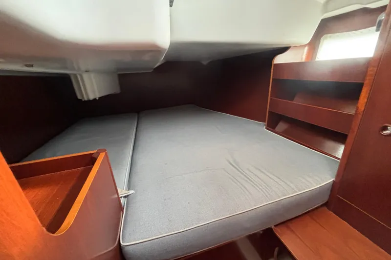 A Domani Yacht Photos Pics Interior cabin of 2002 Beneteau Oceanis 411 sailboat with wooden shelves and bed.