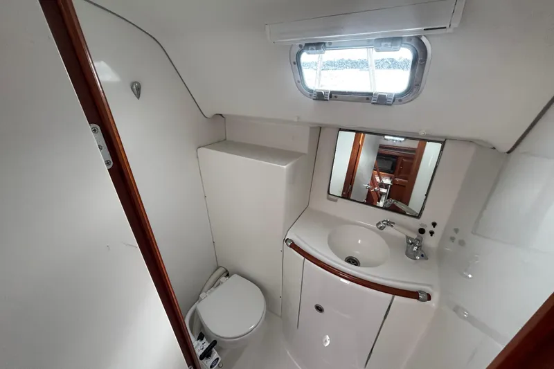 A Domani Yacht Photos Pics Bathroom interior of 2002 Beneteau Oceanis 411 yacht with sink, toilet, and mirror.