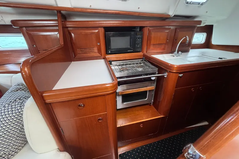 A Domani Yacht Photos Pics 2002 Beneteau Oceanis 411 yacht kitchen with wood cabinetry, stove, microwave, and sink.