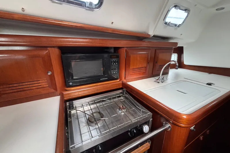 A Domani Yacht Photos Pics Galley kitchen in 2002 Beneteau Oceanis 411 yacht with stove, microwave, and sink.