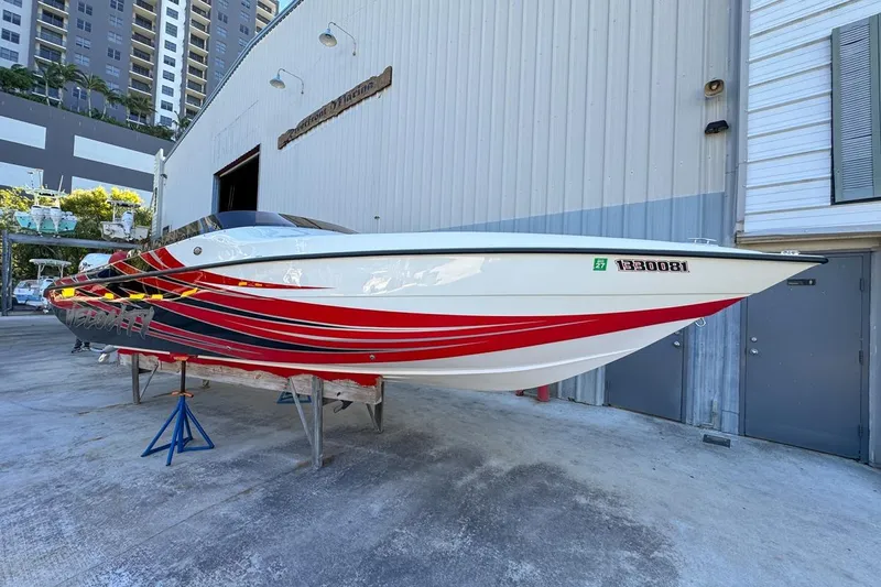 Yacht Photos Pics 2022 Velocity 290sc speedboat with red and black stripes, displayed on stands outside a marina.