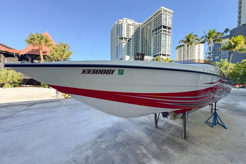  Yacht Photos Pics 2022 Velocity 290sc speedboat with red accents, docked near modern high-rise buildings.